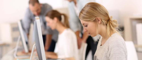 Young girl in office working on desktop computer 600x254